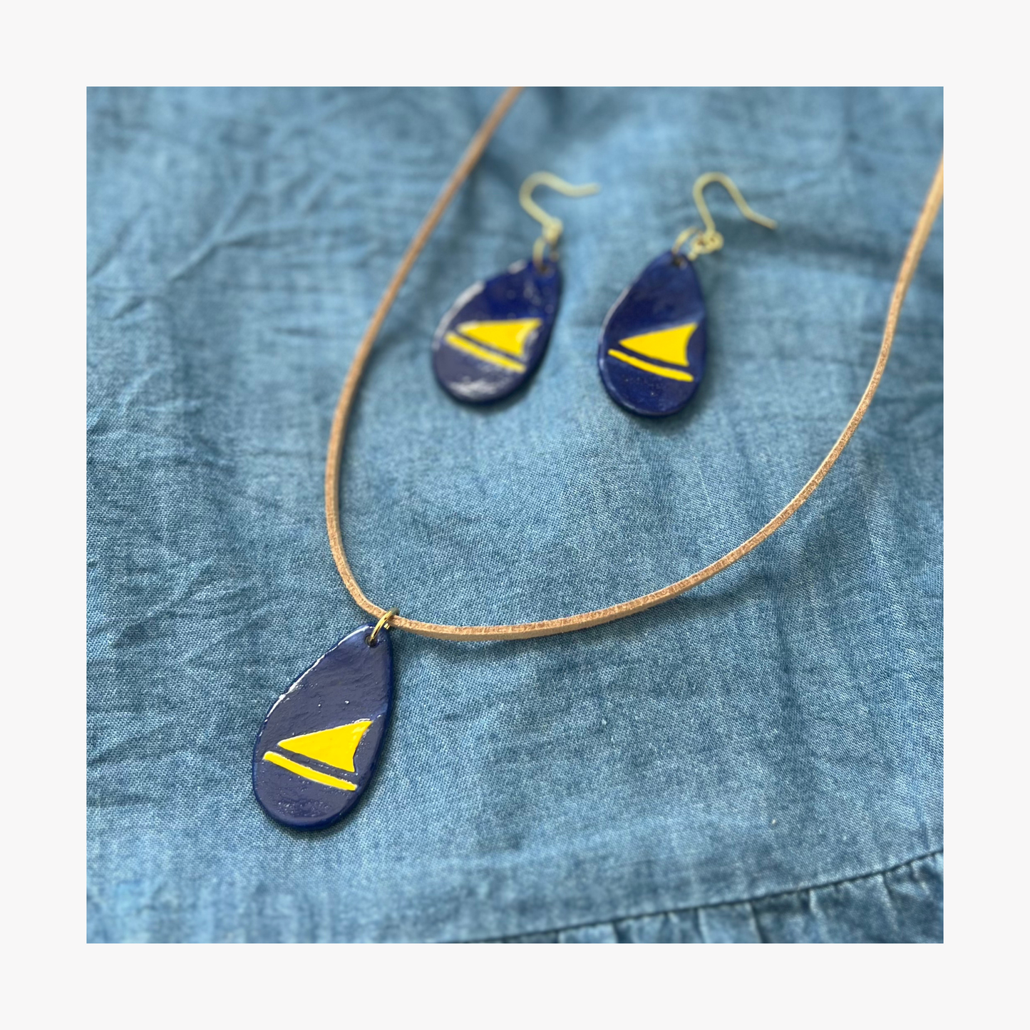 Navy blue and yellow teardrop-shaped Tokelau jewellery set on a denim background
