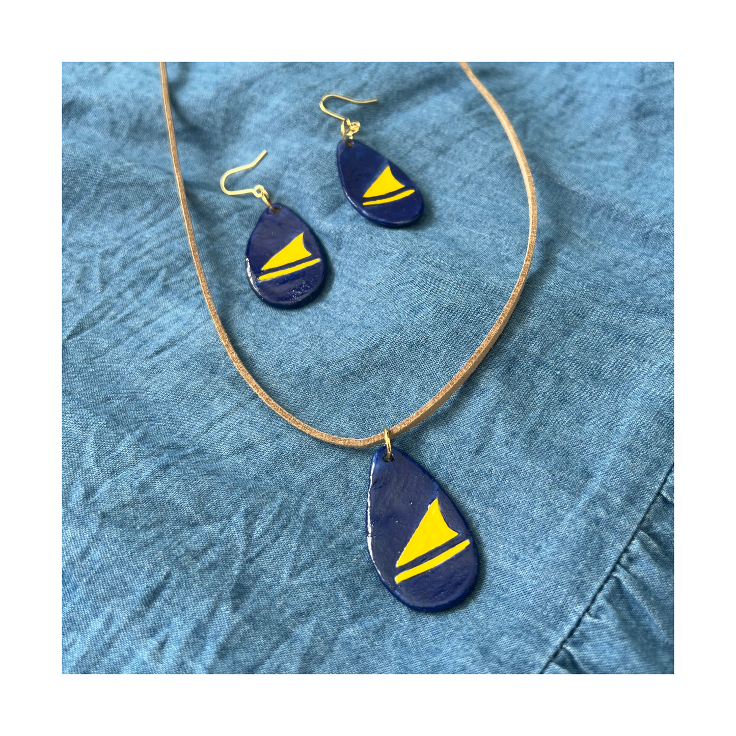 Jewelry set with blue and yellow teardrop-shaped pendants on a denim background
