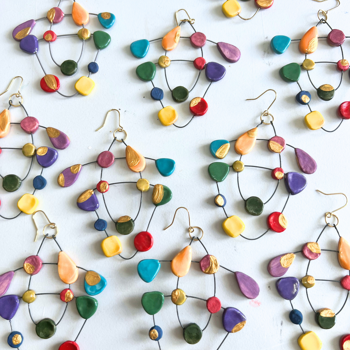 A stunning collection of My Voice of Colours ceramic earrings arranged on a white table, showcasing their unique, vibrant designs as a beautiful piece of wearable art.