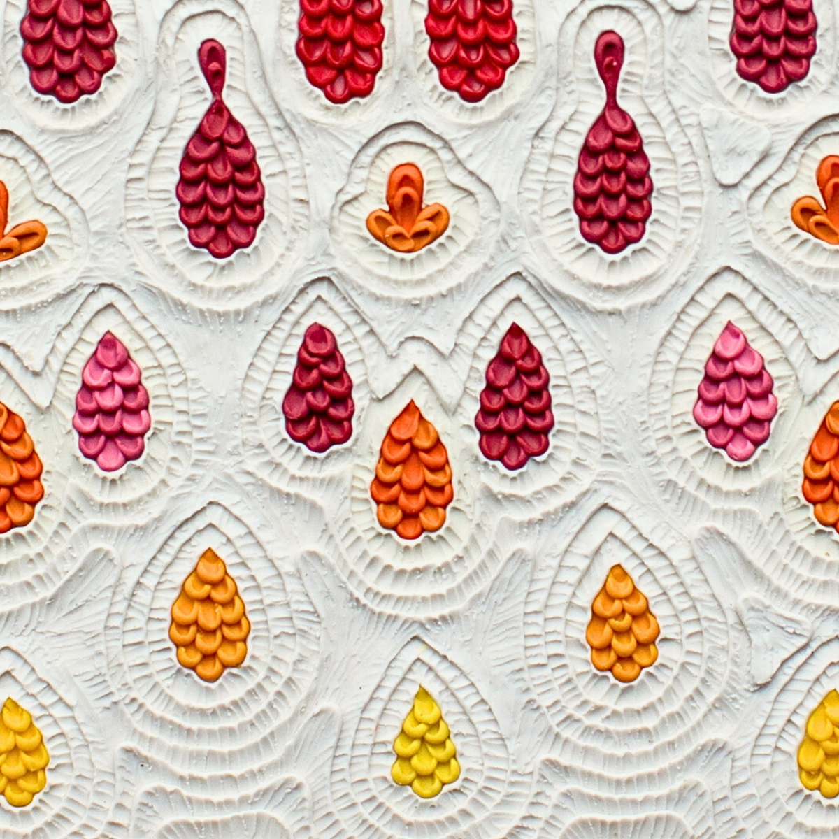A close-up of ''Receive'' plasticine art print, a textured white piece with pattern featuring repeating teardrop shape in red, magenta, orange, and yellow. Art by New Zealand clay artist Emy Oikawa.