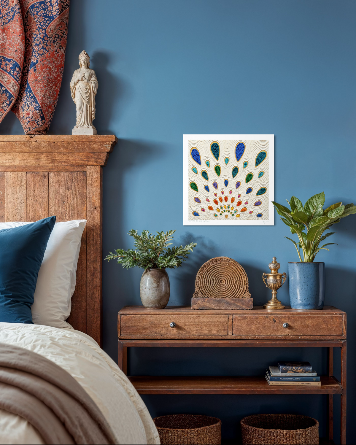 A abstract art print called ''Growth'' by clay artist Emy Oikawa. A colorful peacock feather-like shapes expanding outwards. The print hangs on a blue wall in a styled bedroom. The scene includes a wooden bed frame, nightstand, plants, woven baskets, and decorative objects.