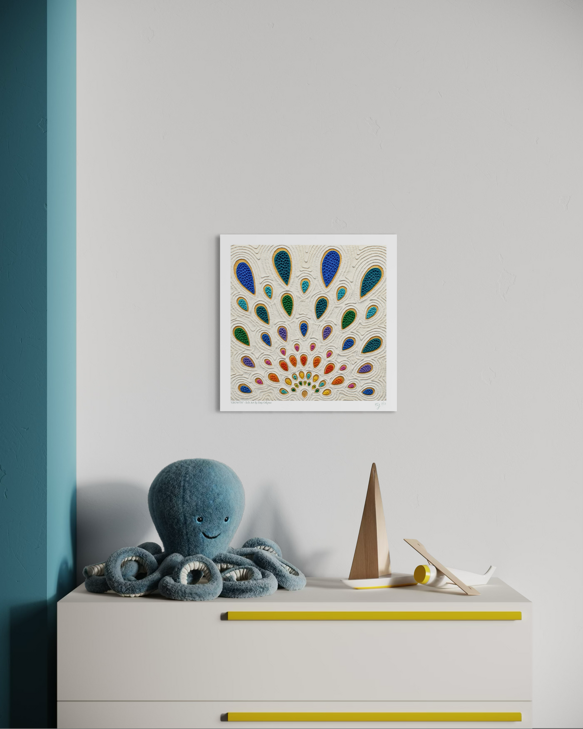 A square wall art print with a colorful drops pattern called ''Growth'', hangs on a light gray wall above a white dresser with yellow handles. A blue octopus plush toy and a small wooden sailboat sit on the dresser. Art print by Emy Oikawa from Eclo Art.