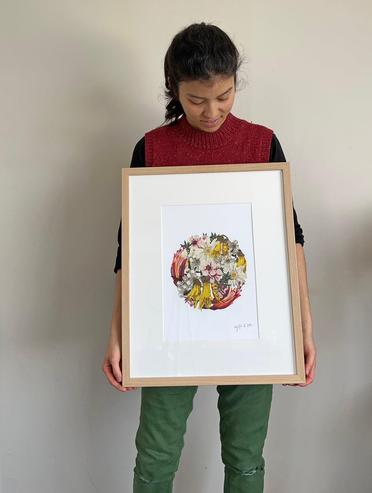 Emy Oikawa holding the framed 'My Floral Sunshine' clay art piece, a collaboration with artist Anna Mollekin.