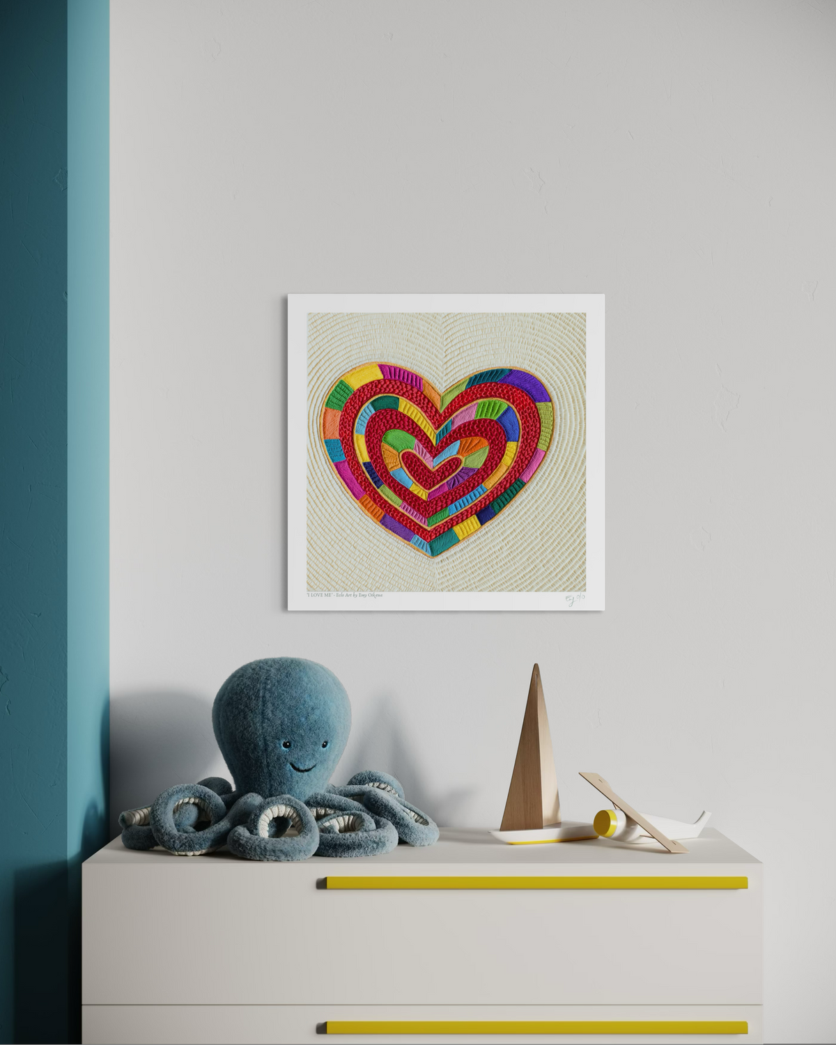 A fine art print featuring ''I Love Me''  colorful, layered heart made plasticine clay by Emy Oikawa from Eclo Art,, displayed on a light gray wall above a white dresser with toys in a styled kids room setting.