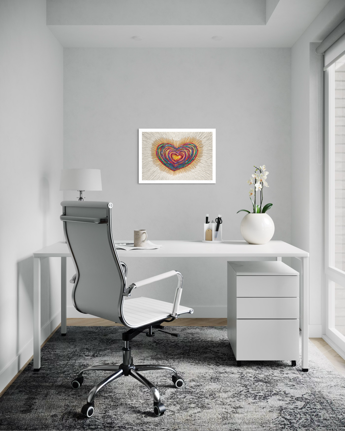 A modern home office setup featuring a white desk, a gray and white swivel office chair. On the wall above the desk is a framed heart-shaped art print called ''Only Love'' by clay artist Emy Oikawa from Eclo Art.