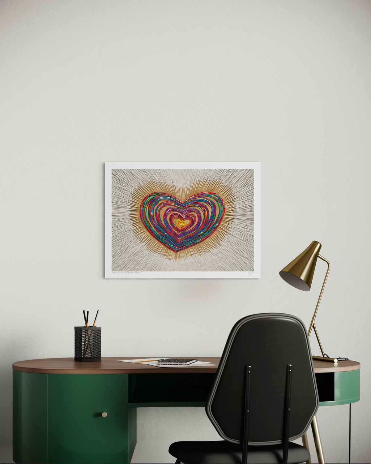 An A3 art print featuring a colorful, concentric heart design called ''Only Love'' created by clay artist Emy Oikawa from Eclo Art. Displayed on a light gray wall above a modern desk setup with a green desk, black chair, and gold lamp.