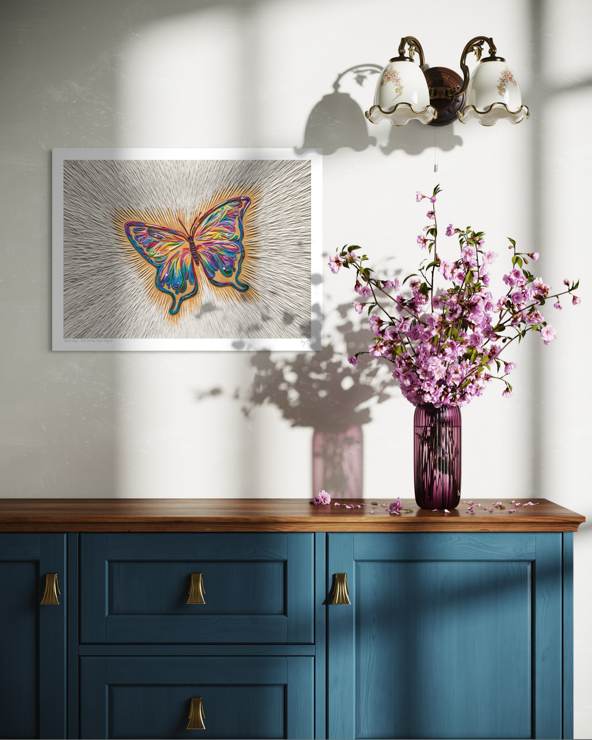 An A3 butterfly art print called ''Spirit Sign'' by clay artist Emy Oikawa from Eclo Art, hangs on a white wall above a blue wooden cabinet, with a purple vase of pink blossoms.