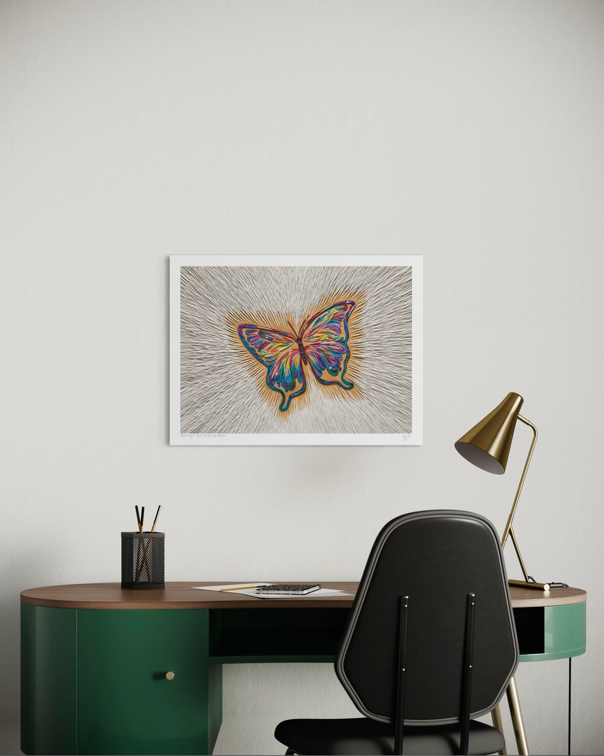 An A3 wall art print featuring a colorful butterfly called ''Spirit Sign'' made by artist Emy Oikawa from Eclo Art, on a textured gray background, displayed above a green desk with a black chair and a gold desk lamp in a modern room setting.