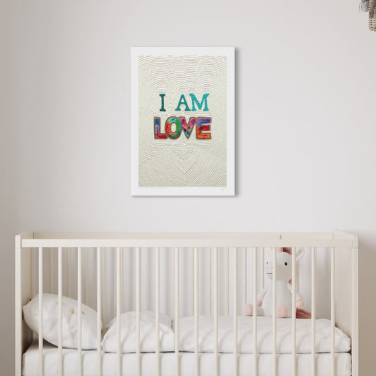 close up video of an A3 wall art print with the words 'I AM LOVE' in colorful textured letters hangs above a white crib in a softly lit nursery. Art by New Zealand artist Emy Oikawa from Eclo Art.