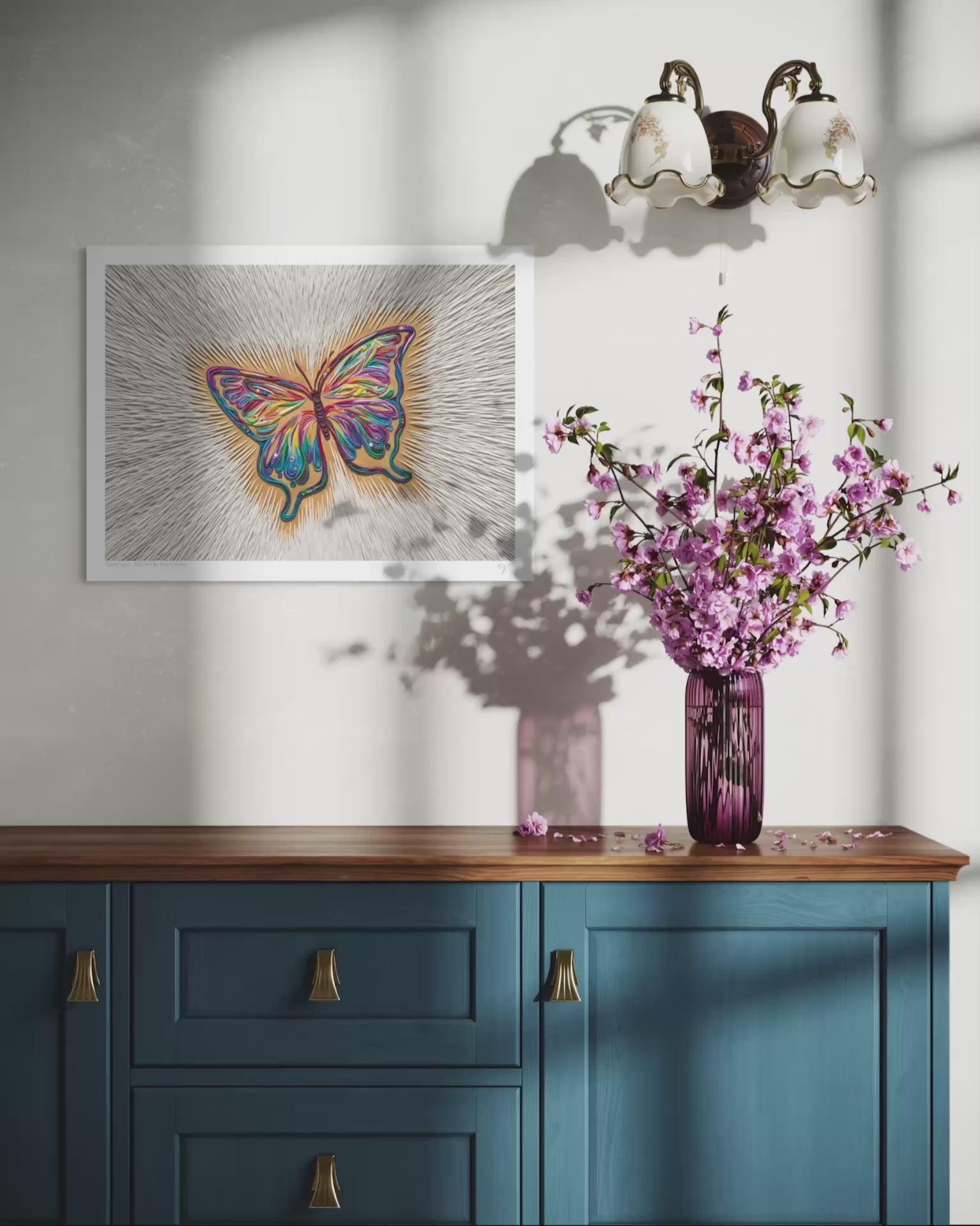 Close up video of an A3 butterfly art print called ''Spirit Sign'' by clay artist Emy Oikawa from Eclo Art, hangs on a white wall above a blue wooden cabinet, with a purple vase of pink blossoms.